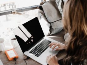 close up photography of woman sitting beside table while using macbook