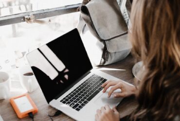 close up photography of woman sitting beside table while using macbook