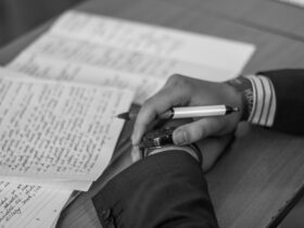 grayscale photography of person holding pen | i'mBiking magazine allows writers to submit their creative writing prompts and advertise their blog links for free.